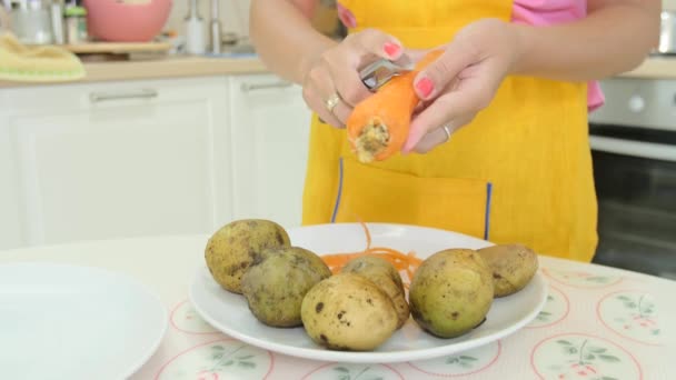 Eine Frau mit orangefarbener Maniküre, die eine Karotte schält — Stockvideo