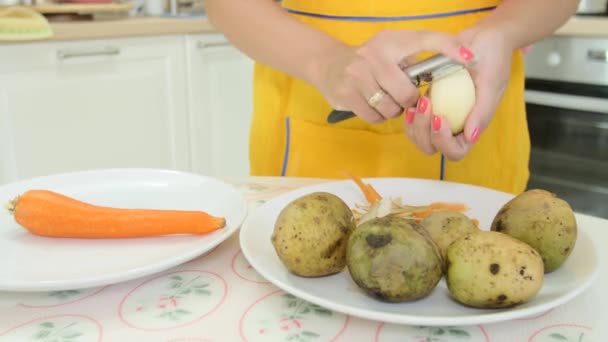 Eine Frau mit orangefarbener Maniküre beim Schälen einer Kartoffel — Stockvideo