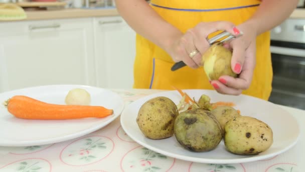 Eine Frau mit orangefarbener Maniküre beim Schälen einer Kartoffel — Stockvideo