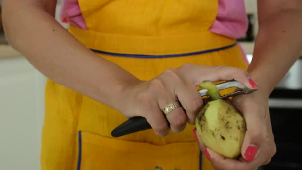 Женщина с апельсиновым маникюром чистит картошку — стоковое видео