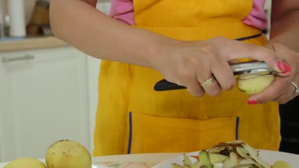 Une femme avec une manucure orange épluchant une pomme de terre — Video