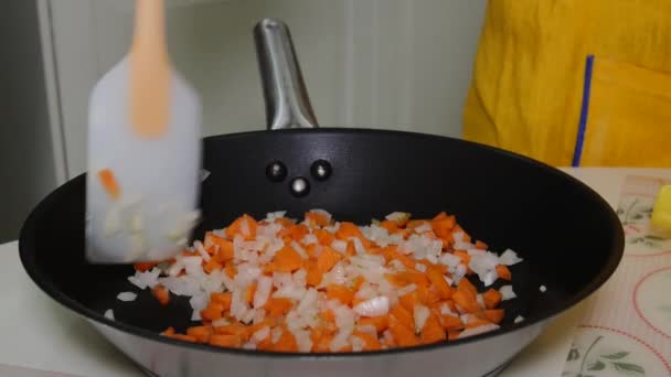 Una mujer mezcla verduras picadas en una sartén — Vídeos de Stock