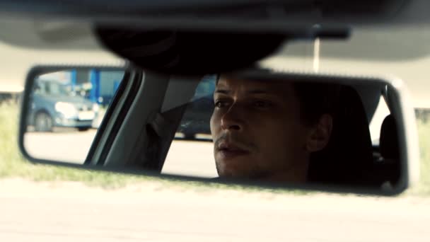 El hombre se sienta en el coche. Cara de reflexión en el espejo retrovisor del coche . — Vídeo de stock