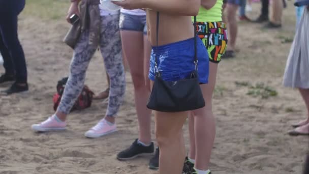 ST. PETERSBURG, RUSSIA - JULY 18, 2015: VK FEST. Girl in a green T-shirt and blue shorts dancing and eating at a beach party — Stock video