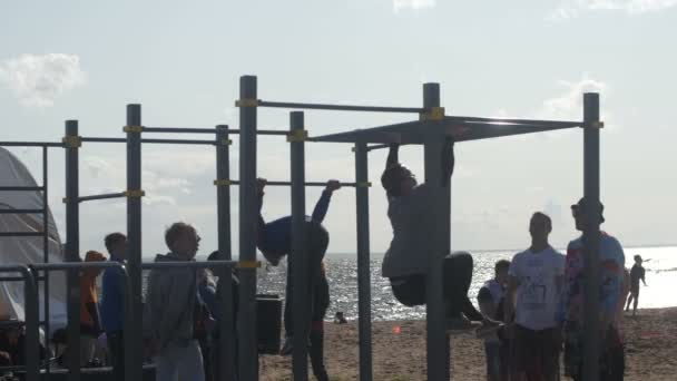 Санкт-Петербург, Російська Федерація - 18 липня 2015: ВК Fest. Чоловіки роблять силові вправи на підтягань тренажерний зал на пляжі — стокове відео