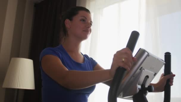 Woman exercising at home with a stationary bicycle — Stock Video