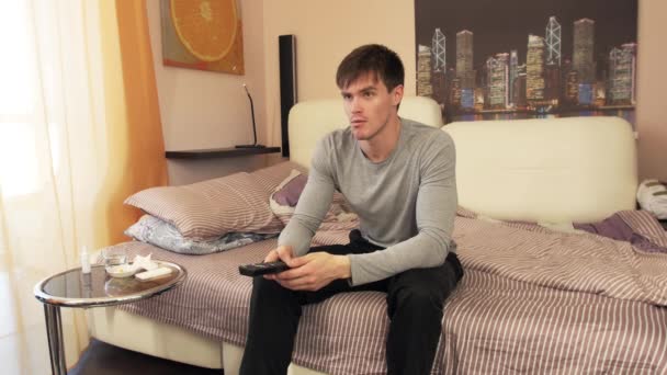 Man zittend op bed, Tv kijken en houden van externe — Stockvideo