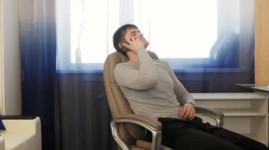 Telefonda konuşurken bir sandalyede oturan yetişkin adam