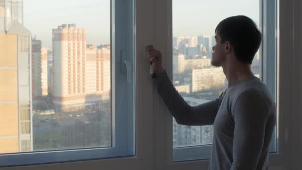 Чоловік в скляному будинку дивиться на вигляд надворі — стокове відео