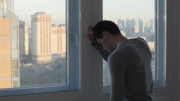 Беспокойный человек стоит и плачет у окна — стоковое видео