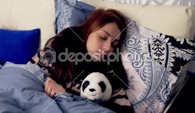 Panda oyuncak ile yatakta uyuyan hasta genç kadın