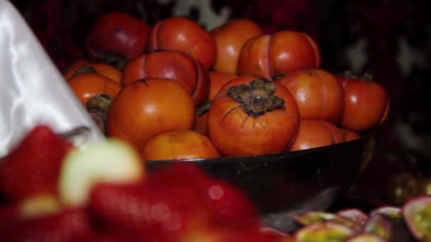 Persimmon in black plate focus in, strawberry on a white plate focus in. — Stock Video