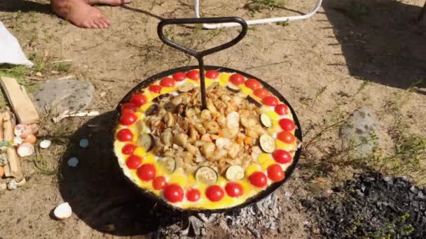 Skålen med en hållare lura potatis och grönsaker på en brasa i solig sommardag — Stockvideo