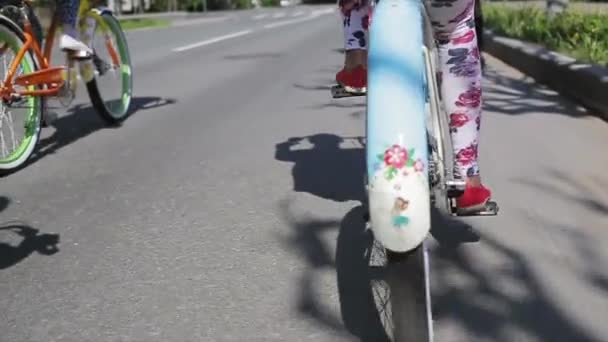 Lado posterior de la niña en bicicleta con otras personas, la rueda de enfoque en hacia fuera. Movimiento lento . — Vídeos de Stock