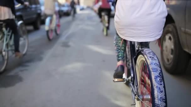 Lato posteriore della ragazza in bicicletta tra gli altri ciclisti nella giornata estiva. Rallentatore — Video Stock