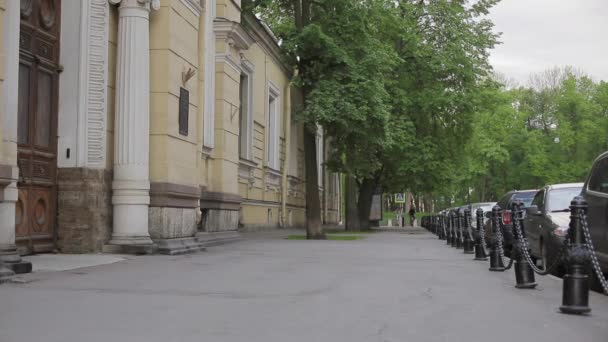 View of city street with green trees and couple on bicycles in summer evening. — Stock Video