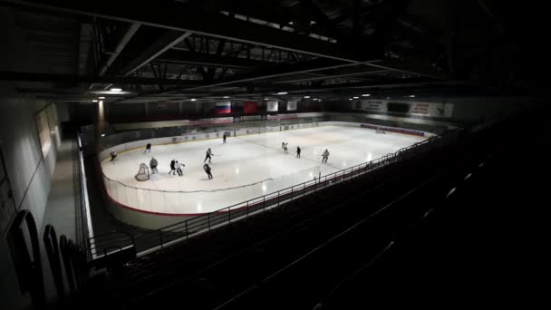 Uitzicht vanaf de donkere links tribune op hockey op overdekte ijsbaan. Slow motion — Stockvideo