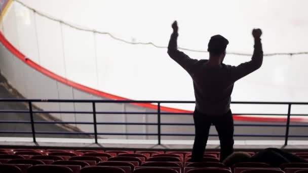 Back side of one hockey fan on tribune, who jumps and rises handes. Slow motion — Stock Video