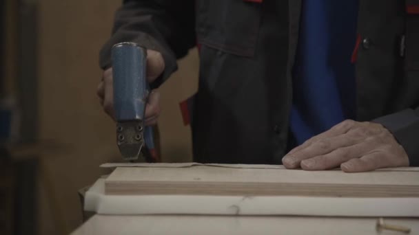 Mann legt mit Klammerpistole Ummantelung um präpariertes Holzbrett — Stockvideo