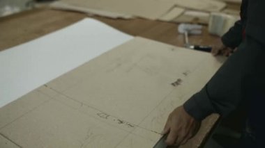 Adam hazır karton alır ve paralon üzerinde siyah kalemi tarafından çevreleyen.