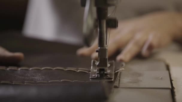 Trabajador hace costuras en el material de cuero mediante la máquina de coser en fábrica. De cerca. — Vídeos de Stock