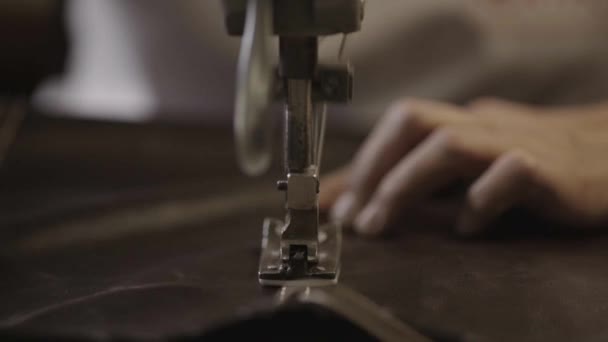 Werknemer maakt naden op lederen materiaal door naaimachine in de fabriek. Close-up — Stockvideo