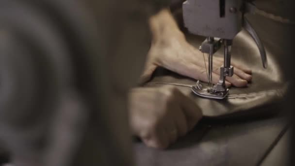 Werknemer maakt naden op lederen materiaal door naaimachine in fabriek. — Stockvideo