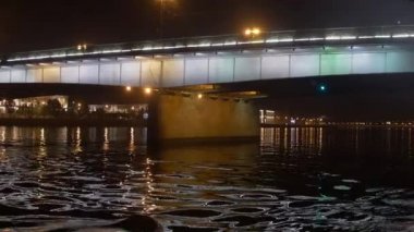 Tekne Nehri Köprüsü altında gecede yüzer. Kamera tekne içinde.