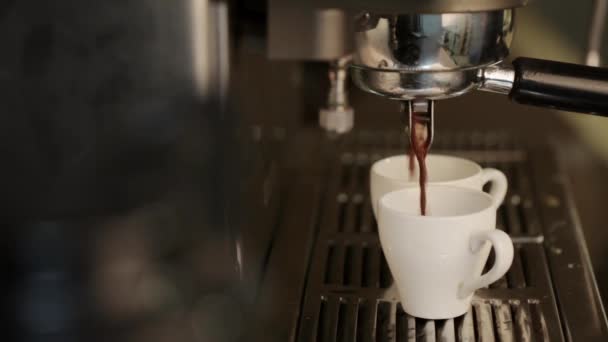 Coffee maker pours hot coffee into two white cups. — Stock Video