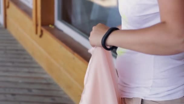 Mãos de mulheres para arrancar costuras de tecido rosa claro longo no dia de verão . — Vídeo de Stock