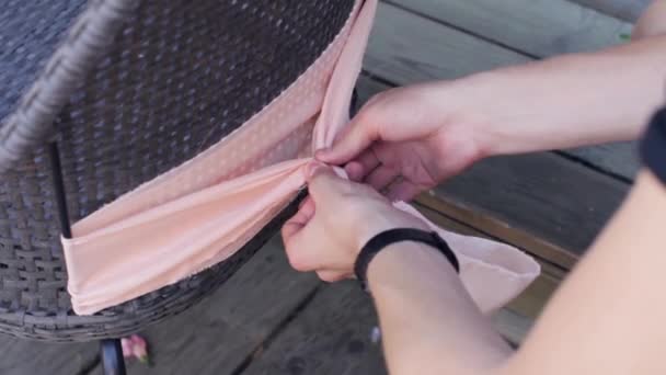 Kvinnans händer dekorera baksidan av stolen av ljus rosa textil i sommardag. — Stockvideo