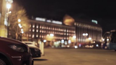 Park etmiş arabaların odak, gece City ile sokak görünümü. İnsanlar.