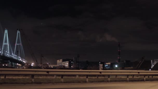 Brug van de snelweg en gebouwen in de stad van de nacht. Rook uit fabriek pipe. — Stockvideo