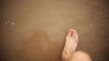Dostum kum plaj, dalgalar nazik yürüyüşte ayaklarını yıka. Yaz. İlk kişi görünümü