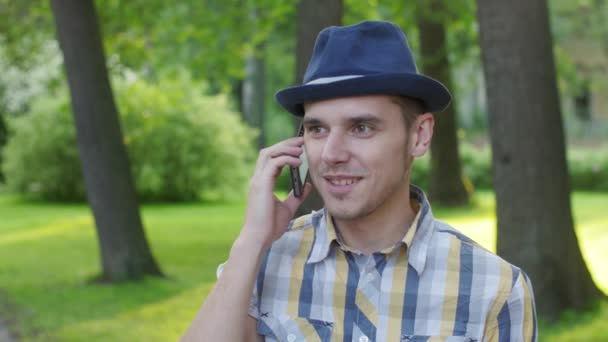 Portrét chlapce v klobouku, jak mluví po telefonu, úsměv. Venkovní. Letní Park. Radostí — Stock video