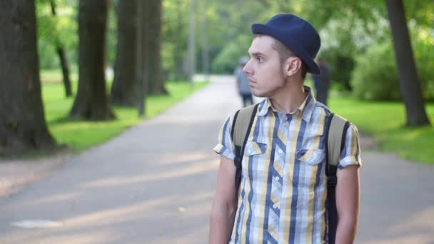 El chico se queda en el parque verde de verano, recibe una llamada por teléfono. Sonríe. Gladness — Vídeos de Stock