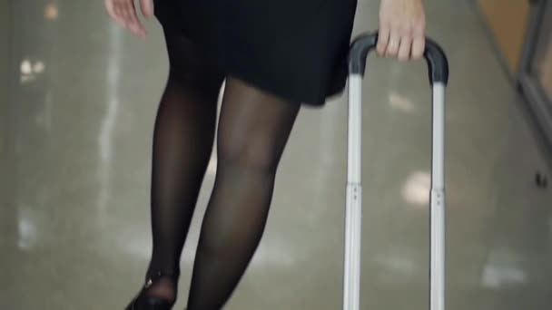 Parte posteriore della donna bionda in scarpa nera sui tacchi passerella passeggiata con valigia. Gambe — Video Stock