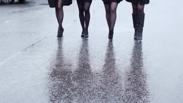 Legs of four woman in shoe on heels walk in lockstep on wet asphalt. Slow motion — Stock Video