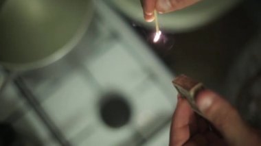 Adam elleri kibriti tutuşturuyor, kibrit kutusu odağına çarpar. Ateşleme gazı sobası odak.