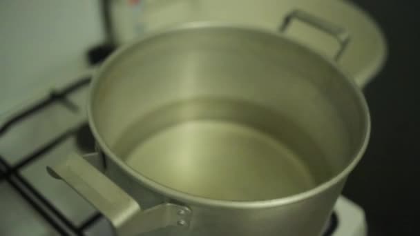 Man hand cover big saucepan with water on gas stove by old round drum plate. — Stock Video