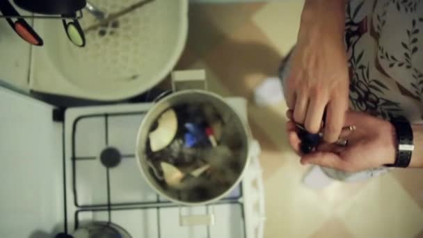 Mann wirft mit ungenießbaren Gegenständen Details aus Musikanlage in Kochtopf — Stockvideo