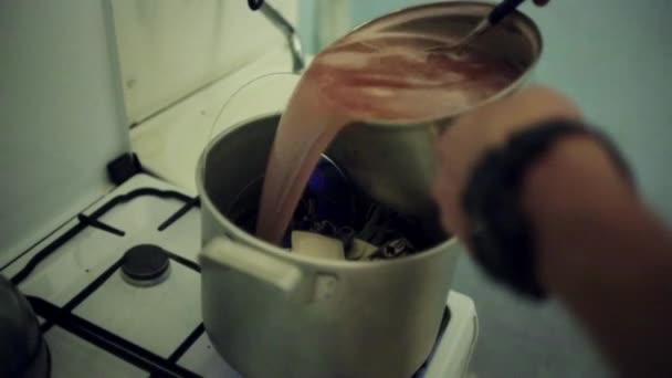 Man hands pours reddish mass into saucepan with inedible objects. Art house cook — Stock Video