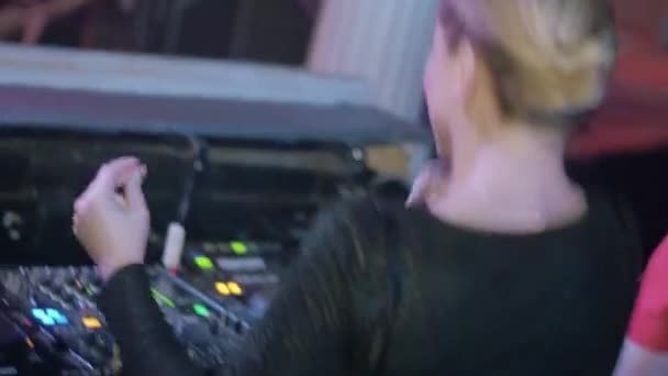 Rückseite des DJ-Girls tanzen, Schultern schütteln, sich am Plattenteller in einem Nachtclub drehen — Stockvideo