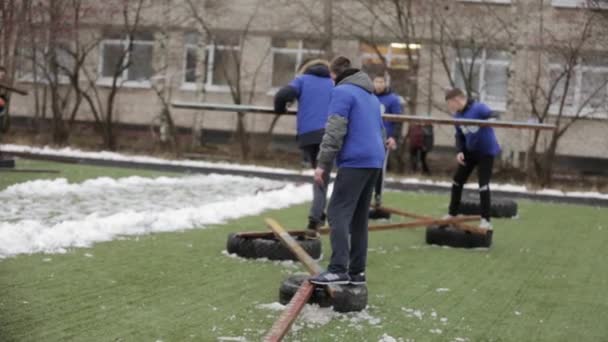 Sankt Petersburg, Rosja-28 listopada 2015: Nastolatki w niebieskie kurtki ustawić most z drewnianej deski na oponach. Szkolenia emercom. — Wideo stockowe