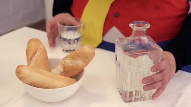 La persona prende il decanter e versa la vodka in vetro, prende baguette dal piatto sul tavolo . — Video Stock