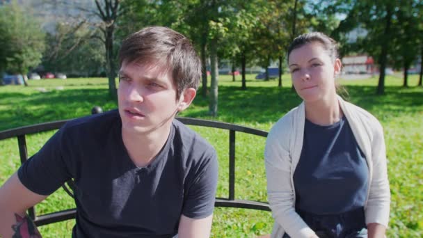 Pareja feliz hablando, sonriendo en el banco del parque — Vídeos de Stock