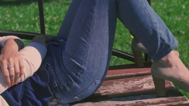 Dziewczyna leży na kolanach na człowieka w parku na ławce — Wideo stockowe