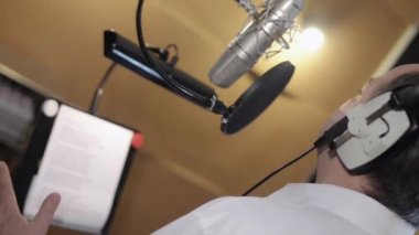 Adam arka yüzünde duygusal şarkı kulaklık mikrofon önünde. Stüdyo