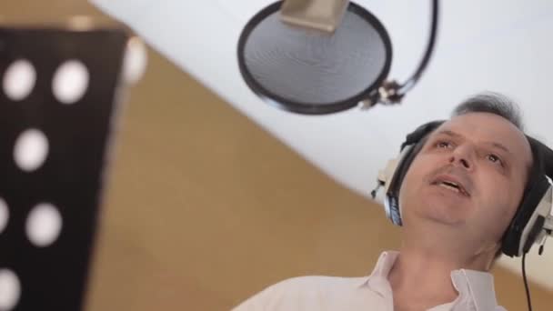 Retrato del hombre cantando en auriculares delante del micrófono. Estudio. Waggle. — Vídeos de Stock