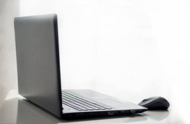 Siyah dizüstü bilgisayar ve beyaz arka planı olan beyaz bir masada kablosuz fare. Nesne ve yaşam tarzı kavramı